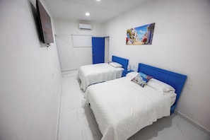 A hotel room with two beds, a TV, an air conditioner, and a painting on the wall.
