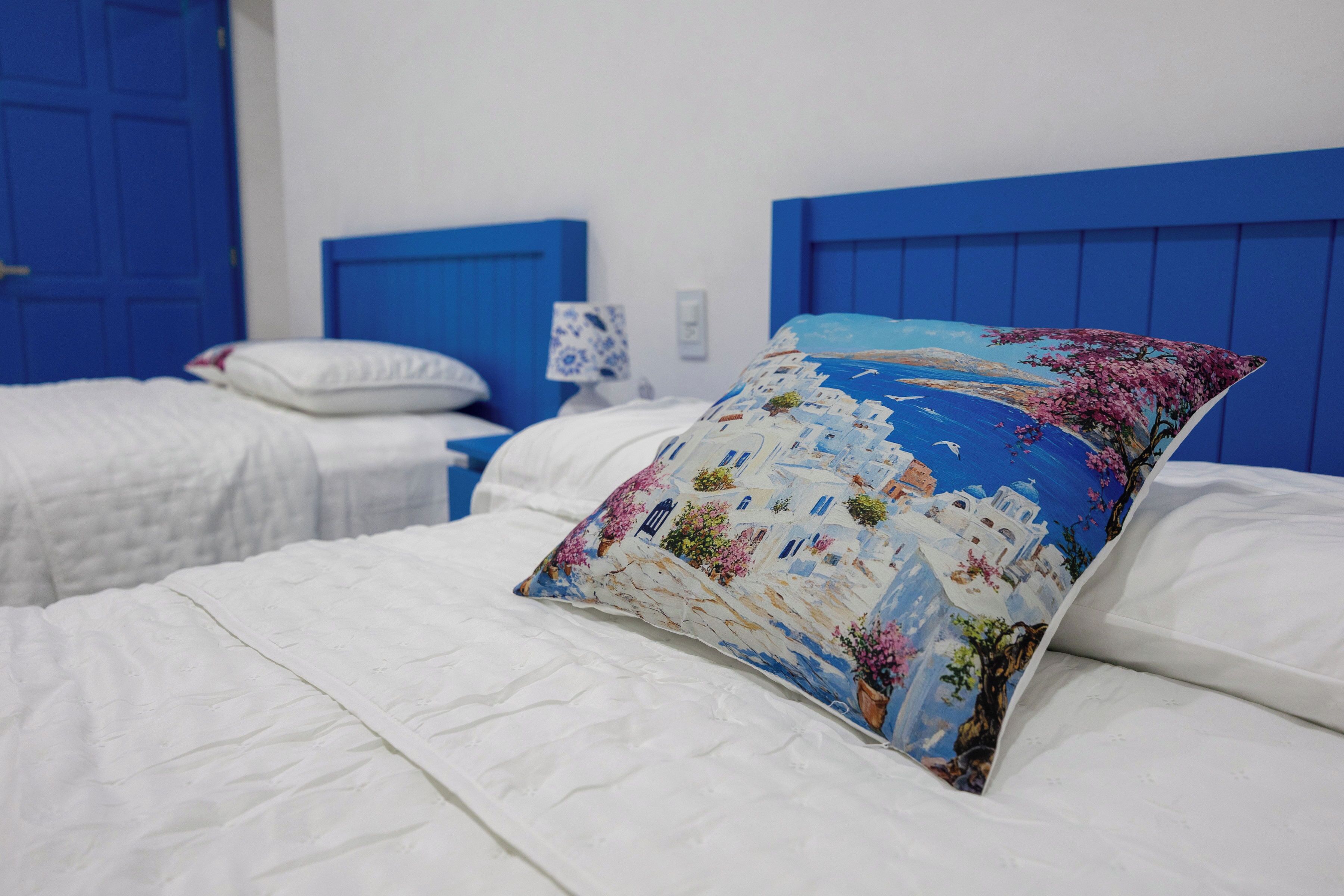A hotel room with two beds, each with white bedding and blue headboards.