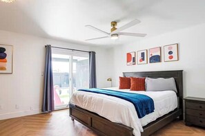 A bedroom with a bed, a ceiling fan, a nightstand, and a sliding glass door leading to an outdoor area. - Scottsdale Hangout | Pool + Putting Green + Games (Scottsdale)