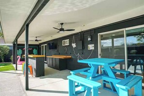 An outdoor patio area with a covered seating area, a pool table, and a ceiling fan. - Scottsdale Hangout | Pool + Putting Green + Games (Scottsdale)