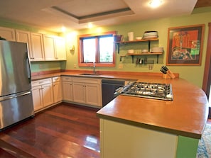 A kitchen with a stainless steel refrigerator, white cabinets, a built-in stove, and a window providing natural light. - Very unique 3-bedroom house on wooded lot near town with great view and privacy. (Homer)
