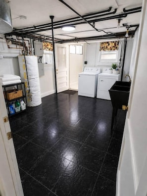 A laundry room with a black tiled floor, a washing machine, a dryer, and a sink. - 2 bedroom Garden duplex by the park (Cheyenne)
