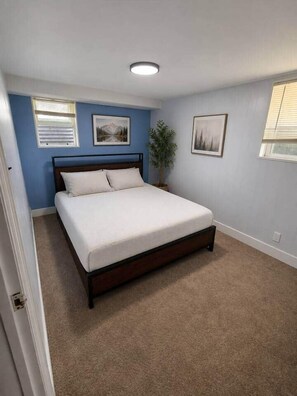 Ein Schlafzimmer mit einem Einzelbett, einer Deckenleuchte und zwei gerahmten Bildern an der Wand.