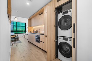 Eine moderne Küche mit Holzausstattung, einem Einbauofen und einer Doppelwaschmaschine.