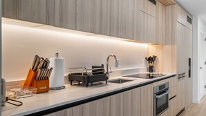 Una cocina moderna con armarios de madera, un lavamanos de acero inoxidable y un horno.