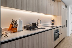 Eine moderne Küche mit Holzausstattung, einer Edelstahl-Spüle und einem Backofen.