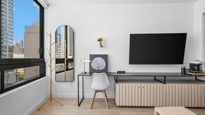 Habitación moderna con un ventanal grande, un escritorio con silla, televisor montado y un espejo decorativo.