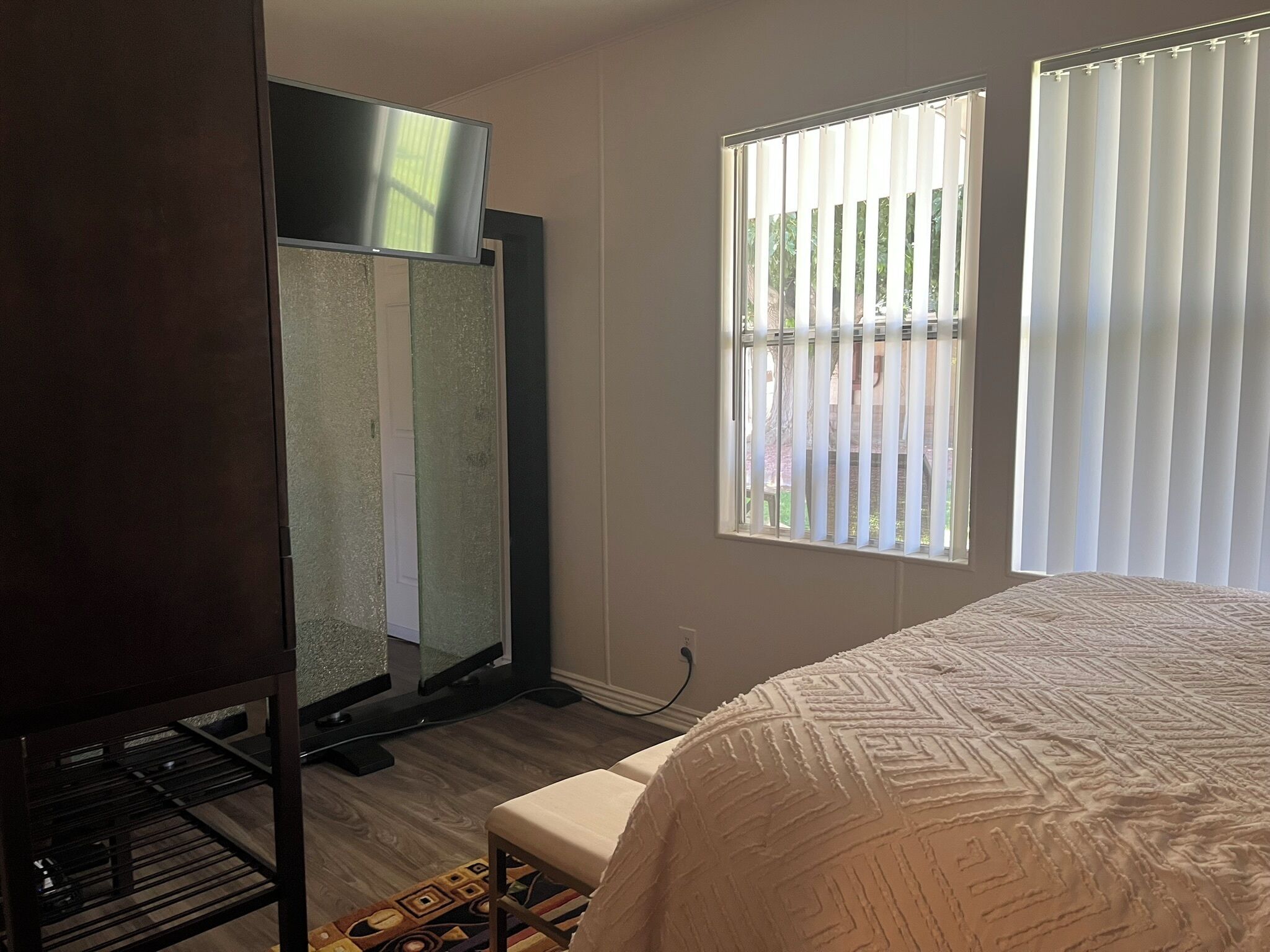 Ein Hotelzimmer mit einem Bett, einem Fernseher, einem Fenster mit Jalousien und einer Tür.