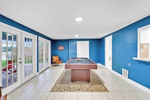 A pool table in a room with blue walls and white trim, a leopard print rug, and a door leading outside. - Large 3-bedroom house lake view Pembroke Pines, Miami (Pembroke Pines)