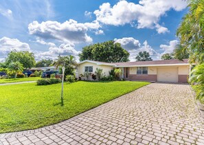 A residential house with a paved driveway, a well-maintained lawn, and a garage. - Large 3-bedroom house lake view Pembroke Pines, Miami (Pembroke Pines)