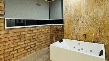 Une salle de bain moderne avec un mur en briques, une grande fenêtre et une baignoire blanche.