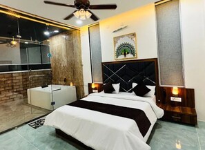 A modern hotel room with a large bed, a separate bathroom, and a glass shower enclosure.