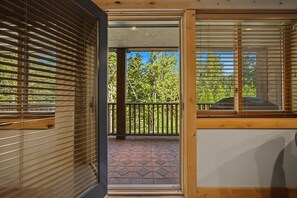An interior space with a view to a balcony, featuring a wooden ceiling, a door, and a window with blinds. - Barlow Pass Condo 201 at South Grand Lodge | In-Room Soaking Tub (Government Camp)