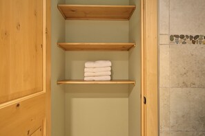 A bathroom with wooden shelves and a tiled wall. - Barlow Pass Condo 201 at South Grand Lodge | In-Room Soaking Tub (Government Camp)