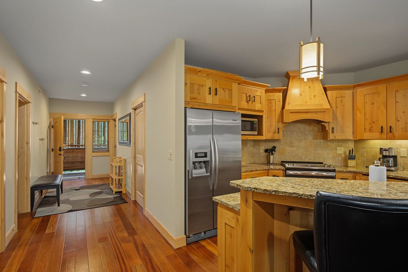 A modern kitchen with wooden cabinets, stainless steel appliances, and a granite countertop.