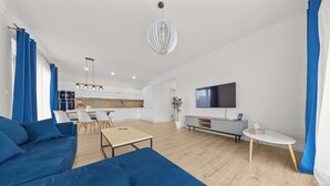A modern living room with a blue sofa, a wooden coffee table, and a TV on a stand. - Klimatizovaný apartmánový dom, vyhrievaný bazén (Dunajská Lužná)
