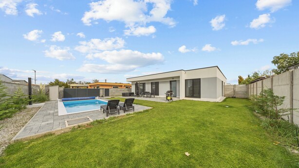 A modern house with a swimming pool, a patio with chairs, and a well-maintained lawn. - Klimatizovaný apartmánový dom, vyhrievaný bazén (Dunajská Lužná)