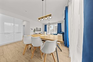 A modern kitchen with white cabinets, a wooden dining table, and four white chairs.