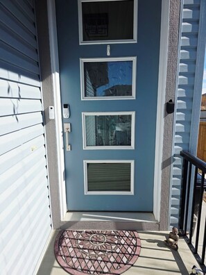 A blue door with three windows, a keypad, and a doormat. - Modern Luxury Home. High Cilings Near Airport. Netflix, Prime, Disney (Leduc)
