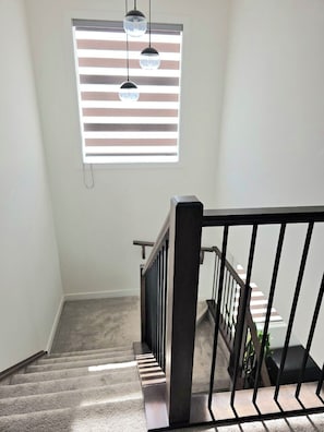 Una escalera con barandilla y una ventana con persianas.