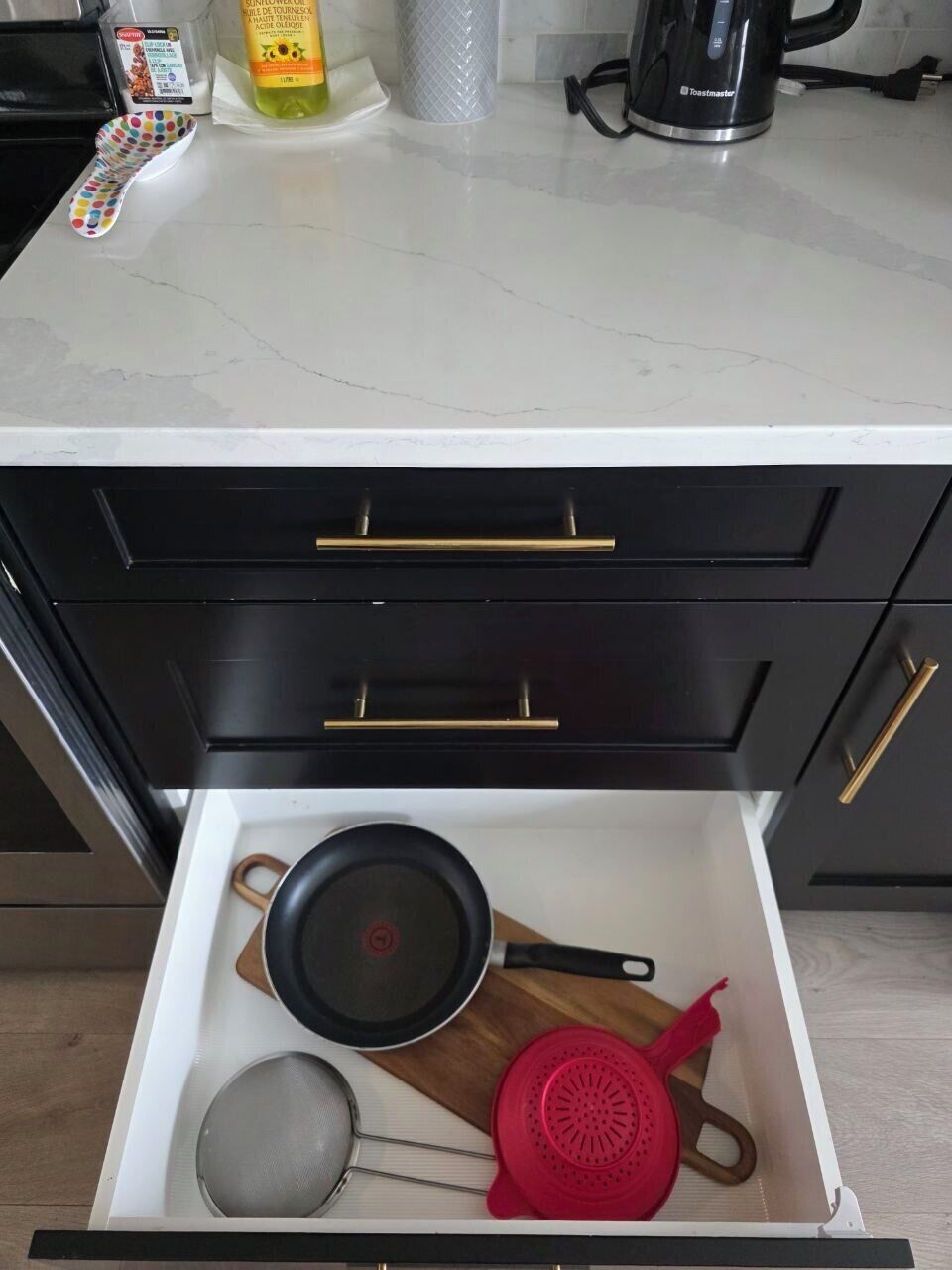 Eine Küchenschublade mit Topf, Sieb und Holzlöffel.