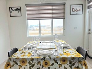 A dining area with a table set for four, a window with blinds, and two framed quotes on the wall. - Modern Luxury Home. High Cilings Near Airport. Netflix, Prime, Disney (Leduc)