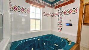 Ein Badezimmer mit einer großen Badewanne, weißen Fliesenwänden und einem Fenster.