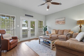 A living room with a brown leather sofa, a wooden coffee table, and a ceiling fan. - The Camp at Timber Ridge - Direct Water Access (Pass Christian)