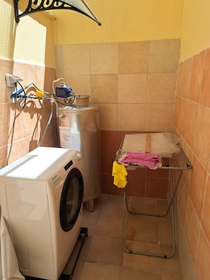 A compact laundry area with a washing machine, a drying rack, and a water heater. - A fully furnished apartment, perfect for relaxing in Puglia (Molfetta)