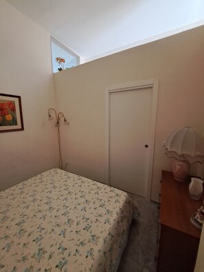 A bedroom with a bed, a door, a dresser, a wall-mounted light fixture, and a framed picture. - A fully furnished apartment, perfect for relaxing in Puglia (Molfetta)