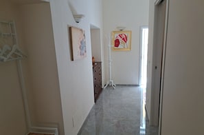 A hallway with a marble floor, a coat rack, and wall-mounted artwork. - A fully furnished apartment, perfect for relaxing in Puglia (Molfetta)