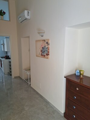 A kitchen with a white cabinet, a white sink, and a stove. There is a white air conditioning unit mounted on the wall. - Fully furnished apartment, perfect for relaxing in Apulia (Molfetta)