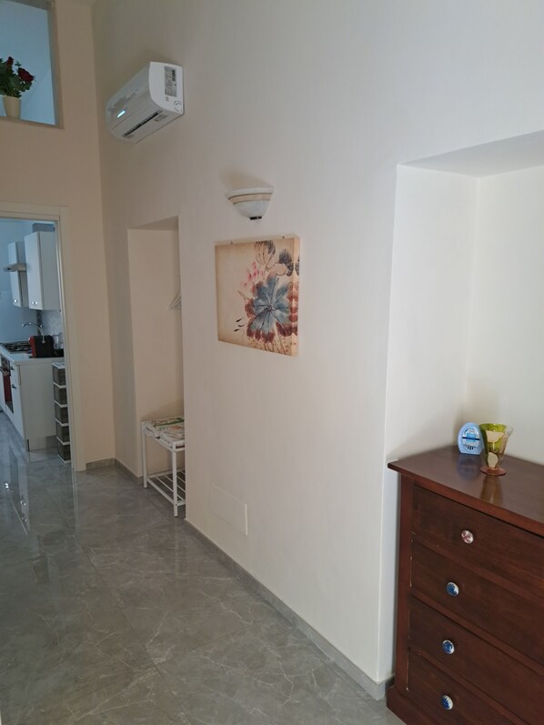 A kitchen with a white cabinet, a white sink, and a stove. There is a white air conditioning unit mounted on the wall. - A fully furnished apartment, perfect for relaxing in Puglia (Molfetta)