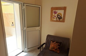 A room with a sliding glass door leading to a balcony, a grey sofa with a decorative pillow, and a framed artwork on the wall. - A fully furnished apartment, perfect for relaxing in Puglia (Molfetta)