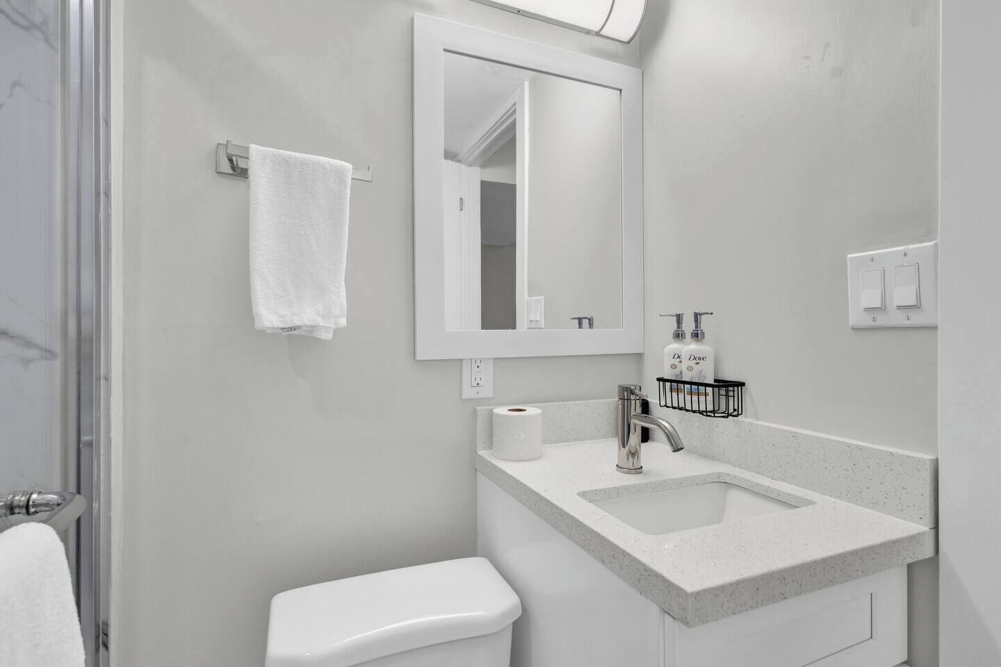 A bathroom with a toilet, sink, mirror, towel rack, and a shower area.