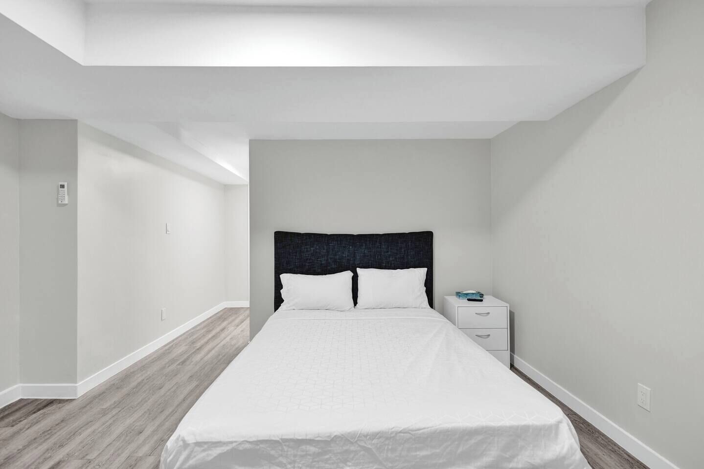 Een slaapkamer met een bed, nachtkastje en een wandklok.