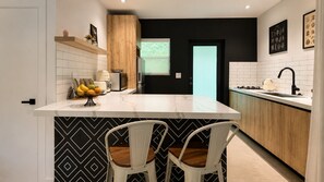 Een moderne keuken met een centraal eiland, witte kasten en een zwart-wit tegelwand.