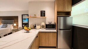 A modern kitchen with a built-in microwave, a refrigerator, and a wooden cabinet. - Peaceful Little Havana Studio/Private Backyard/ Free Parking (Miami)