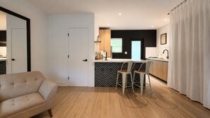 A modern kitchen with a black and white patterned backsplash, a wooden countertop, and two bar stools. - Peaceful Little Havana Studio/Private Backyard/ Free Parking (Miami)