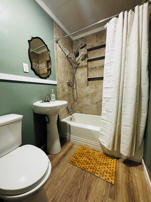 Ein Badezimmer mit Toilette, Waschbecken, Badewanne, Dusche und Spiegel.