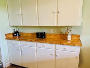 A kitchen with wooden cabinets, a kettle, a toaster, and a knife block.
