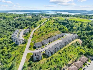 A residential area with modern houses arranged in a curved layout, surrounded by greenery and a lake in the background. - NEW! 6BR | 2 Condos | Sleeps 16| No Stairs (Branson)