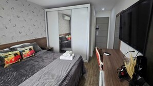 A bedroom with a bed, a wardrobe, a TV, and a mirror. - Vrbo suite farmasi arena, Barra 5min, Riocentro, Rock in Rio 10min, Zona Sul 40min (Rio de Janeiro)