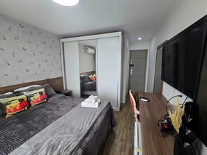 Um quarto com uma cama, um guarda-roupa, uma televisão e um espelho.