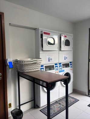 A laundry area with multiple washing machines, a table, and a basket. - Vrbo suite farmasi arena, Barra 5min, Riocentro, Rock in Rio 10min, Zona Sul 40min (Rio de Janeiro)