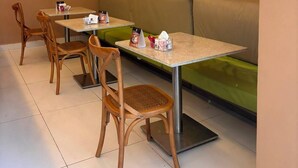 A restaurant interior with tables, chairs, and a green cushioned bench. - Vrbo suite farmasi arena, Barra 5min, Riocentro, Rock in Rio 10min, Zona Sul 40min (Rio de Janeiro)