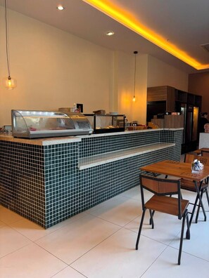 Um café moderno com balcão em azulejo, área de estar e iluminação pendente.