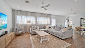 Un salon moderne comprenant un canapé, une table basse et un coin repas avec des chaises.