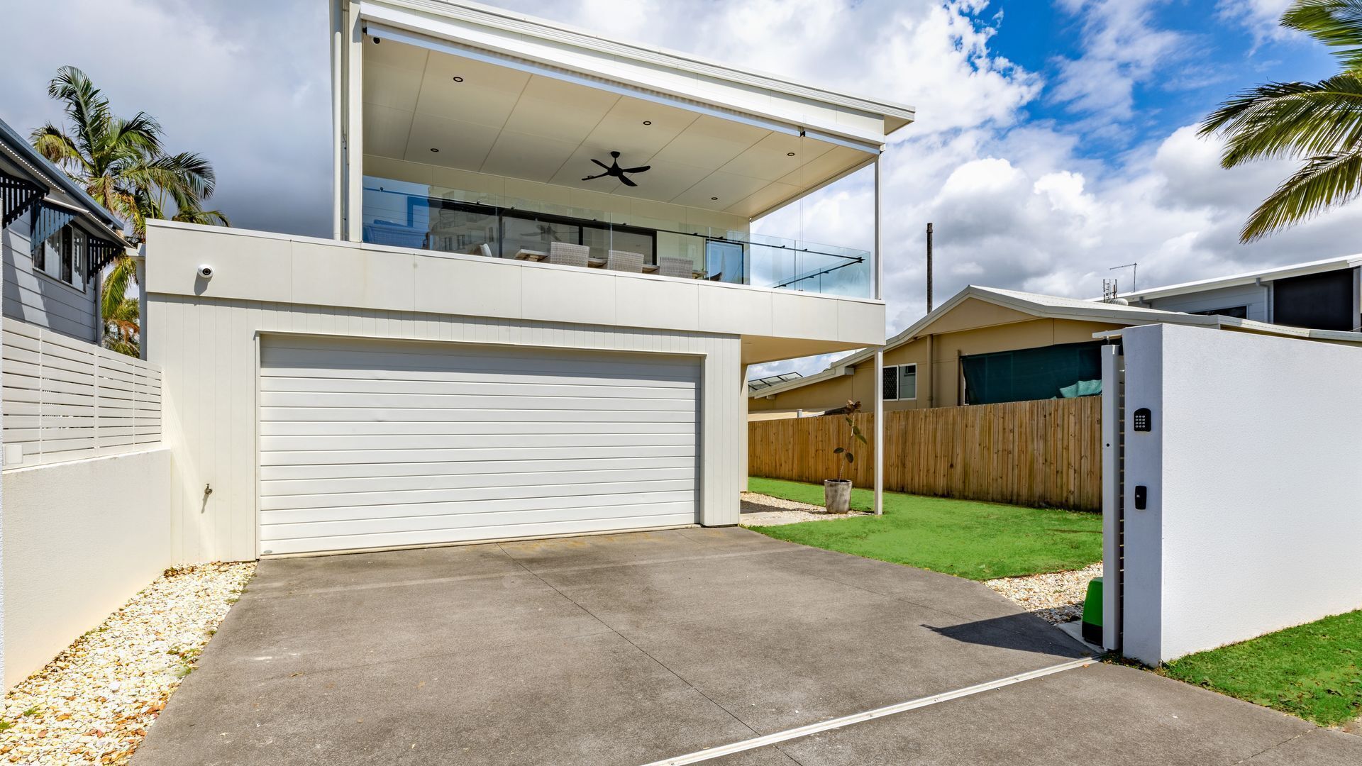 A modern two-story house with a garage, a balcony, and a well-maintained lawn.