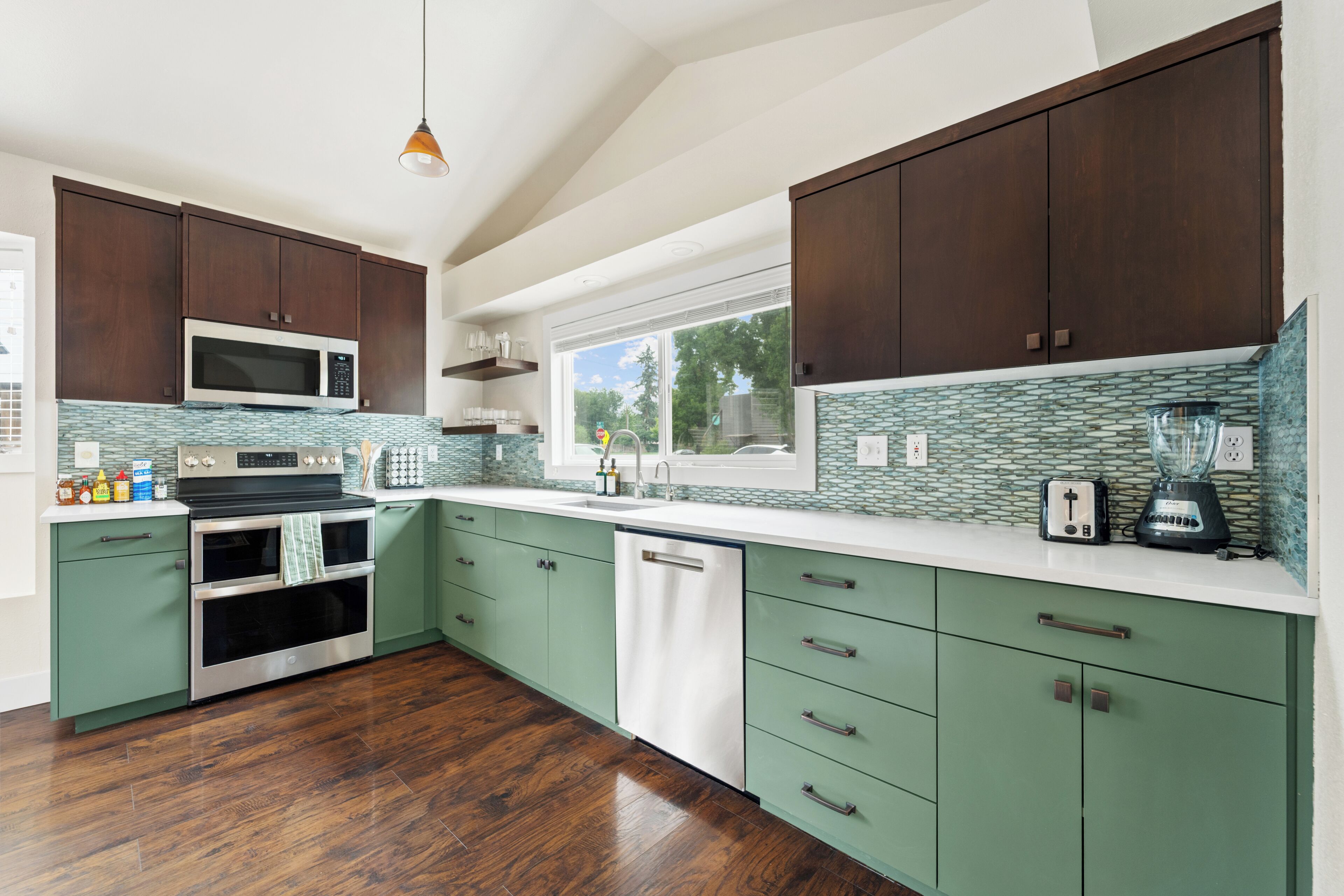 Una cucina moderna con mobili verdi, un forno a microonde, un forno e una finestra con vista sugli alberi.